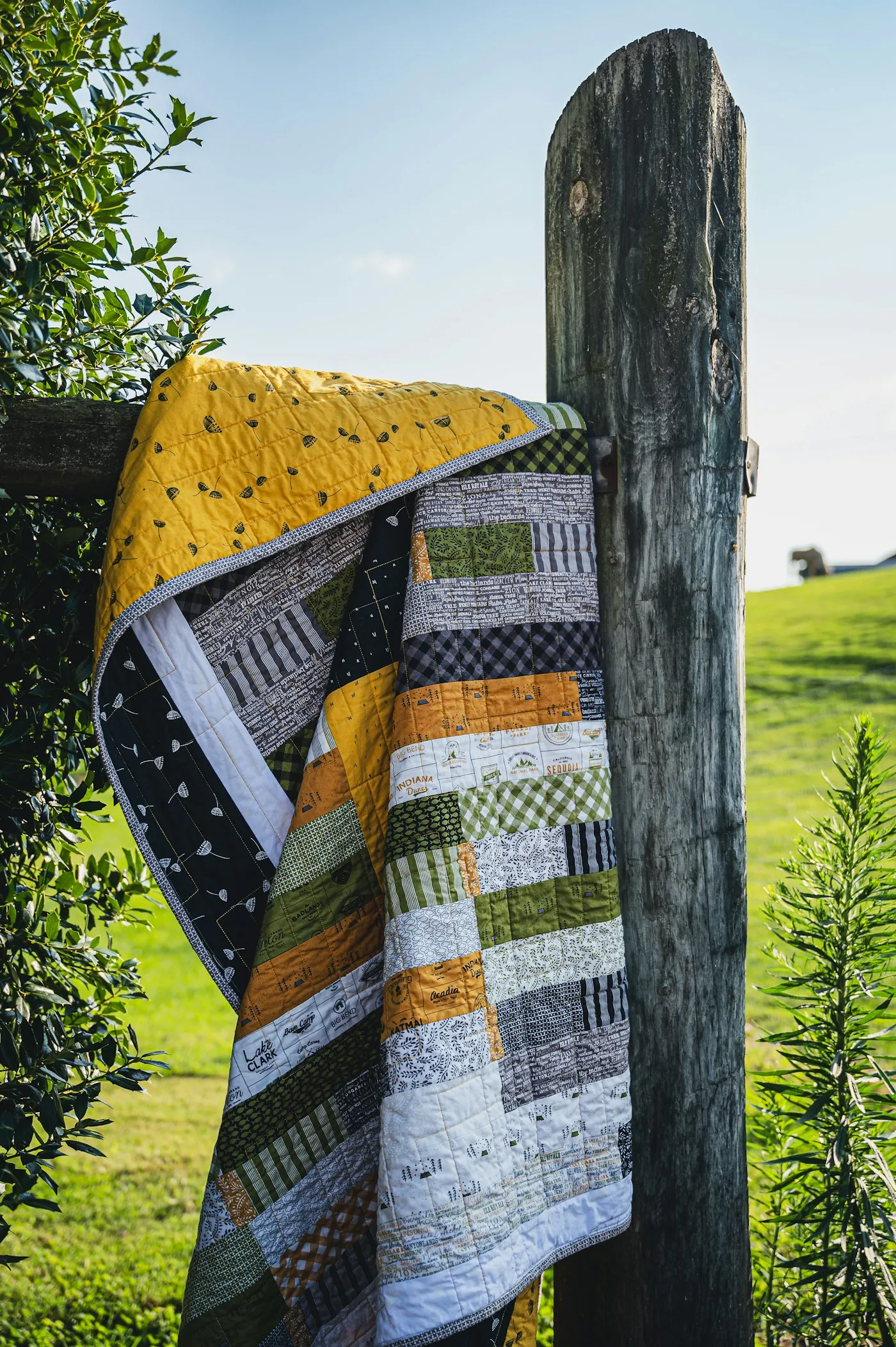 A patchwork quilt drying over a fence post